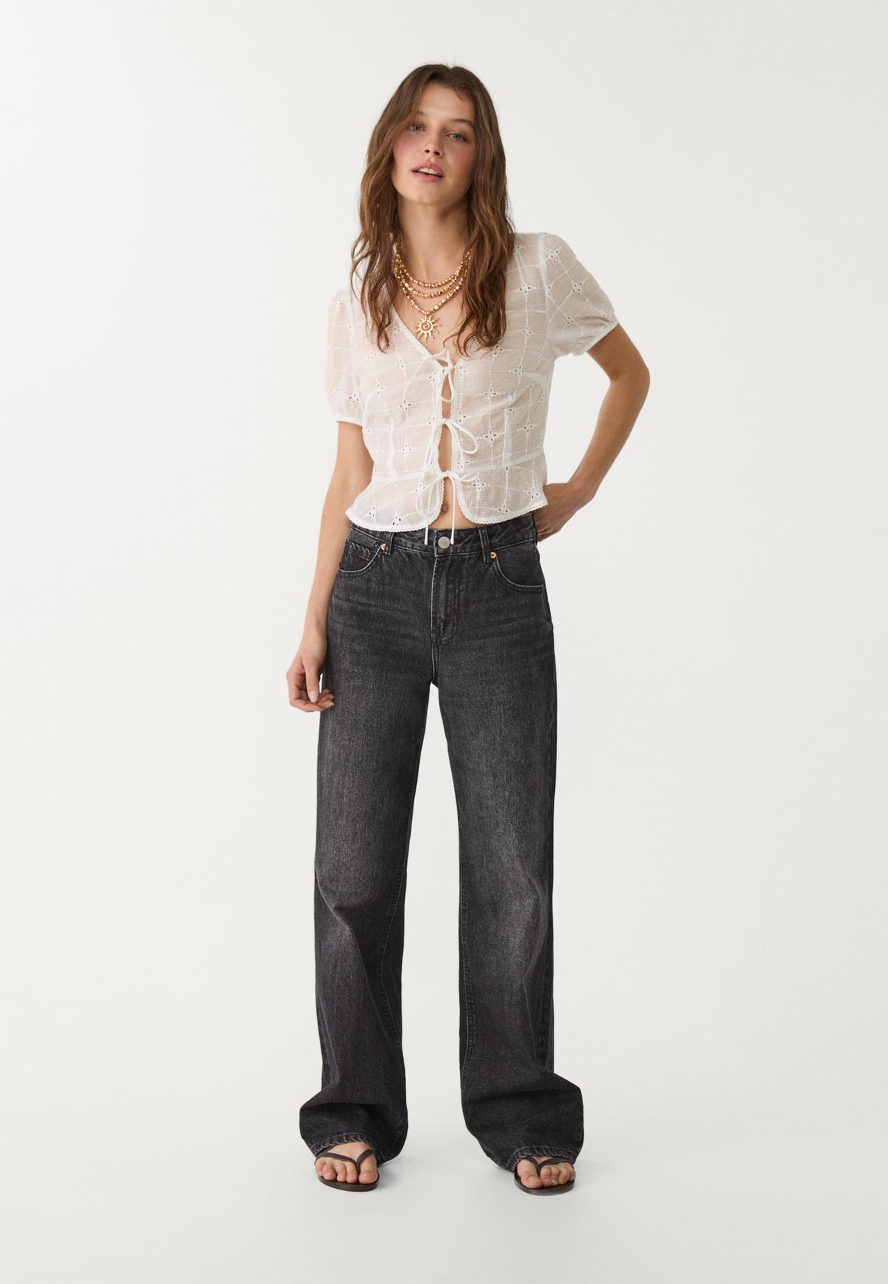 White blouse set with bows and floral embroidery, dark wide-leg jeans, and black sandals.