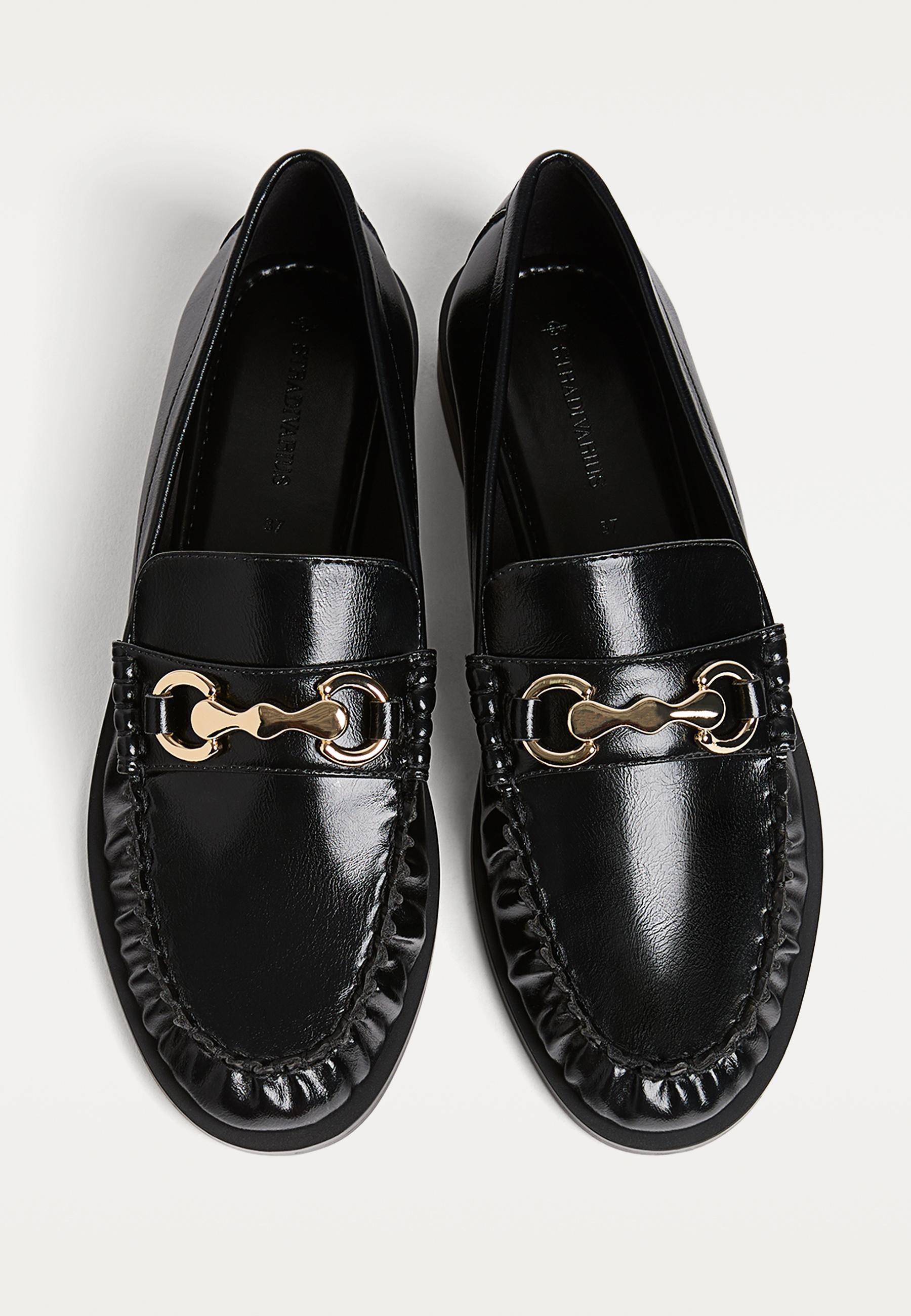 Front view of black loafers with gold embellishment on the vamp