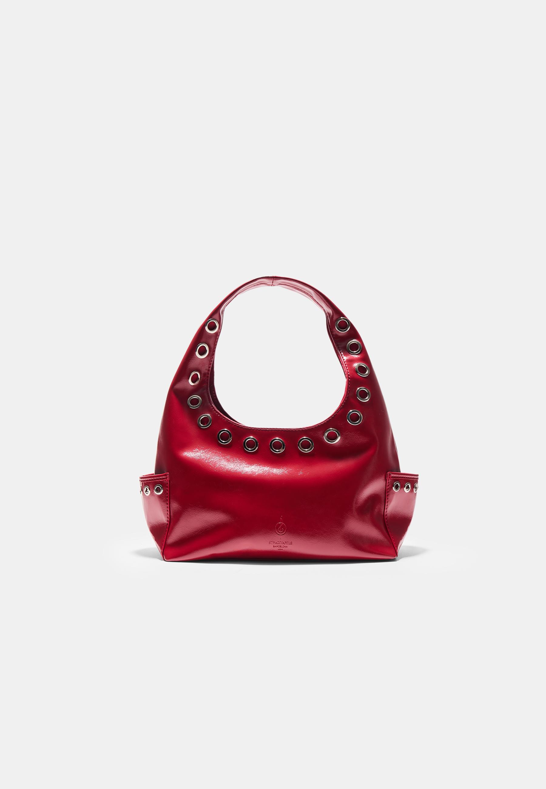 Front view of a red handbag with metal eyelets on the handle and side pockets.