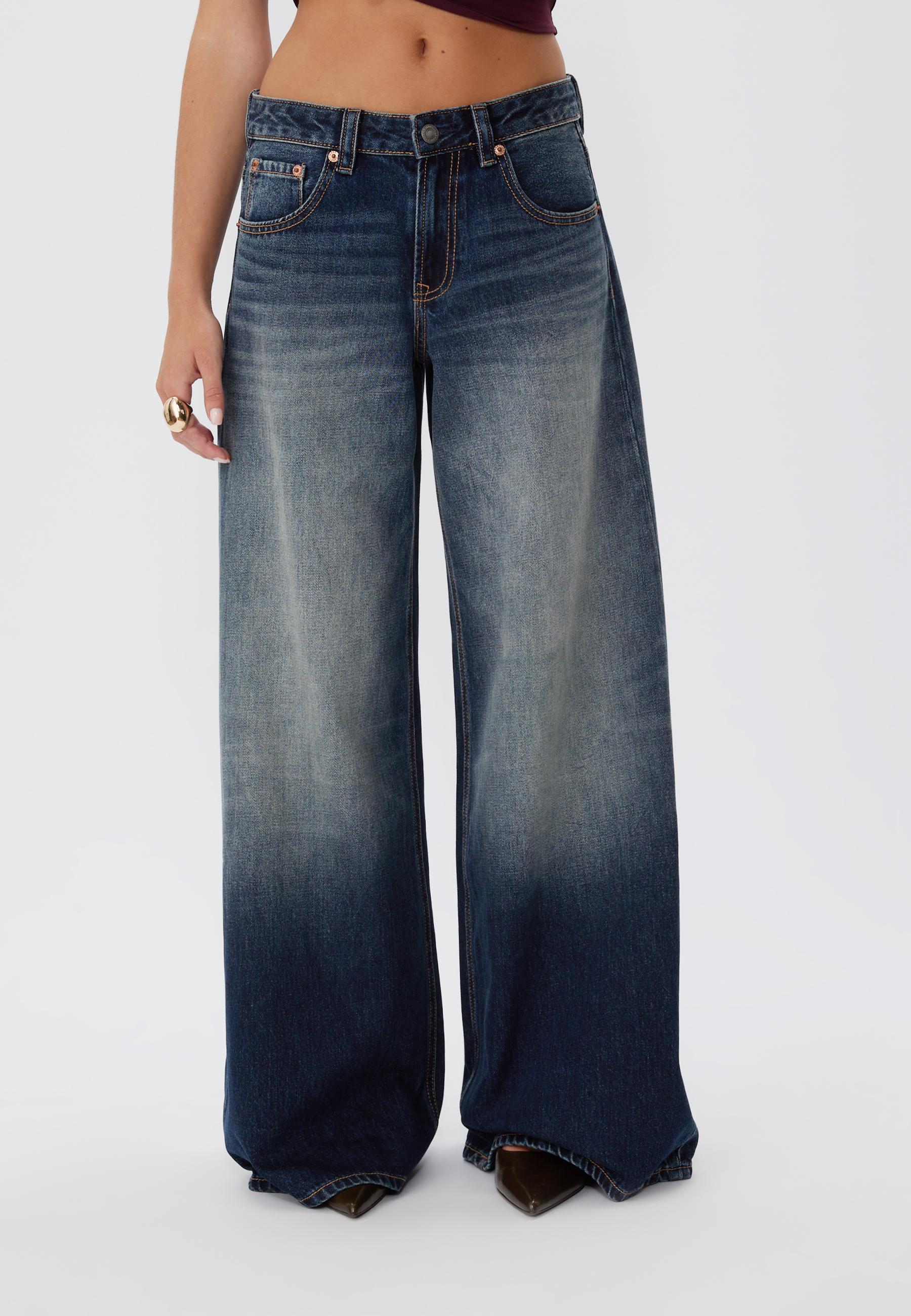 Mid-shot of washed-effect black denim jeans, low-rise, super wide leg, front and back pockets.
